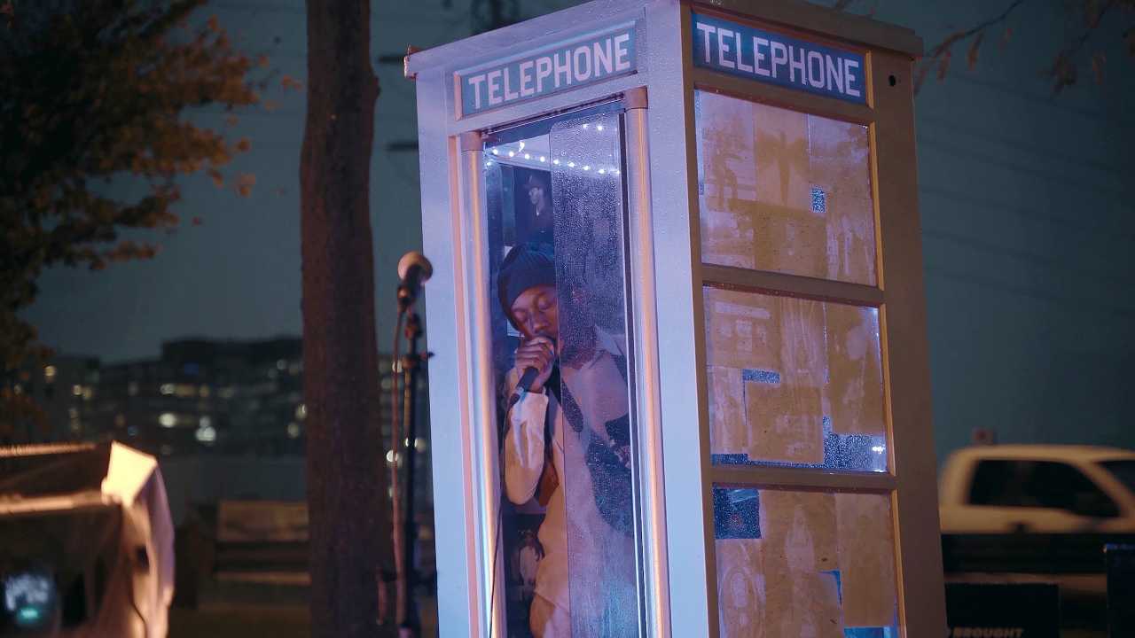 a man singing into a microphone in a phone booth
